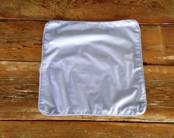 May include: A light blue pillowcase with a white border. The pillowcase is rectangular and made of a smooth, shiny fabric. The pillowcase is on a wooden surface.