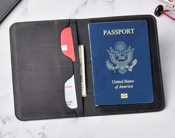 May include: A black leather passport holder with a passport inside. The passport is blue with the words "PASSPORT" and "United States of America" printed on it. The holder has a slot for a credit card and a pocket for cash.
