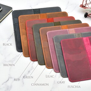 May include: Eight leather passport holders in different colours: black, brown, red, green, cinnamon, lilac, grey, and fuchsia.