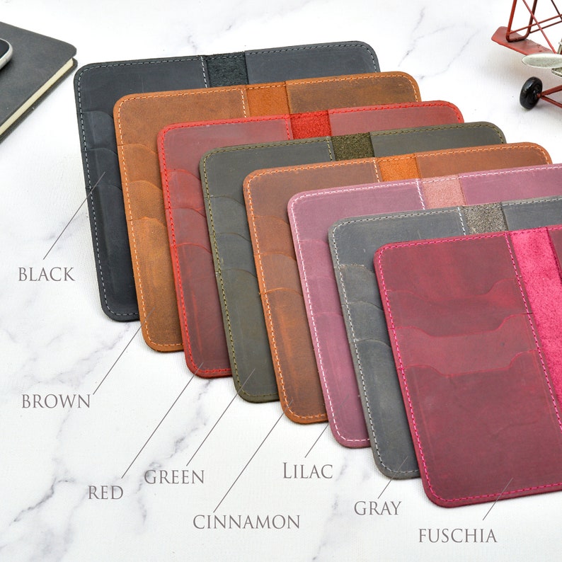 May include: Eight leather passport holders in different colours: black, brown, red, green, cinnamon, lilac, grey, and fuchsia.