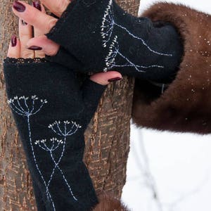 Pu&ograve; includere: Guanti neri senza dita con ricami floreali bianchi e dettagli di perline argentate. I guanti hanno un bordo in pizzo e sono indossati con un cappotto di pelliccia marrone. I guanti sono realizzati in un materiale morbido e caldo.