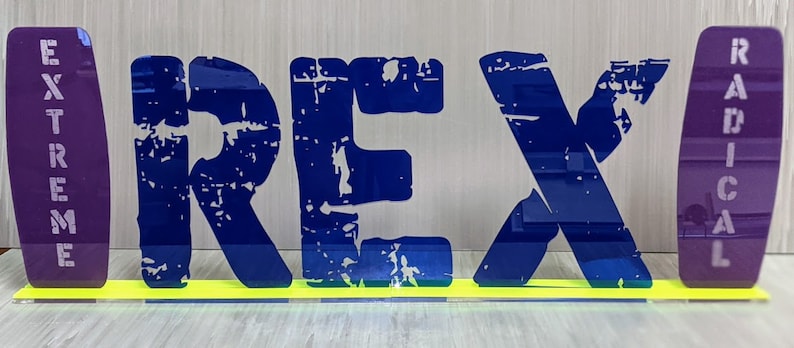 May include: A blue and yellow sign with the word "REX" in large, distressed letters. The sign is flanked by two purple panels with the words "EXTREME" and "RADICAL" written vertically.