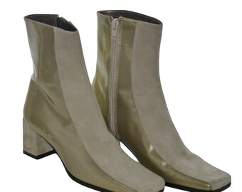 May include: A pair of ankle boots with a square toe and a block heel. The boots are made of a combination of suede and patent leather in a light brown color.