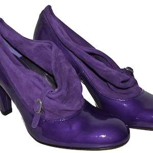 Può includere: Un paio di scarpe con tacco alto viola con un dettaglio in camoscio intorno alla caviglia.