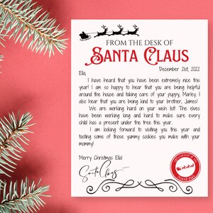 May include: A letter from Santa Claus on cream-colored paper with a red border, featuring a handwritten message and Santa's signature. The letter is dated December 21st, 2022, and includes a North Pole seal. Evergreen branches frame the letter.