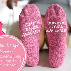 以下が含まれることがあります： 各ソックスの底に「CUSTOM DESIGN AVAILABLE」という文字が印刷されたピンク色のソックスのペアです。