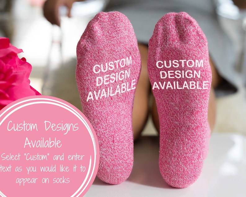 以下が含まれることがあります： 各ソックスの底に「CUSTOM DESIGN AVAILABLE」という文字が印刷されたピンク色のソックスのペアです。