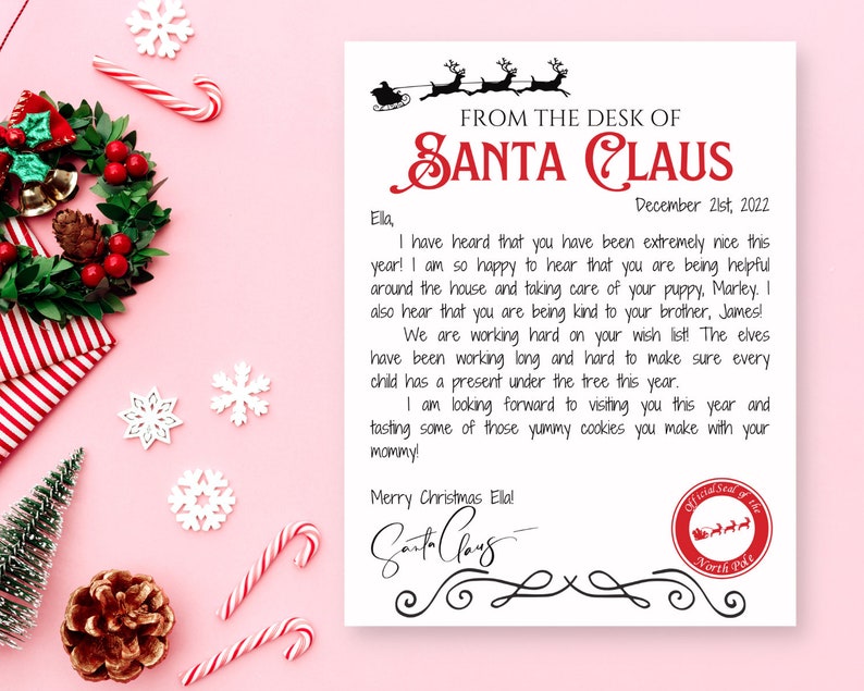 May include: A letter from Santa Claus on white paper with a pink background. The letter is addressed to "Ela" and includes a message, Santa's signature, and a North Pole seal. Christmas decorations surround the letter.