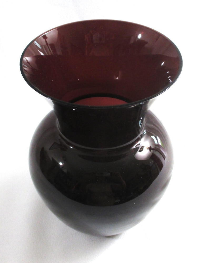 May include: A dark purple glass vase with a wide mouth and a rounded body.