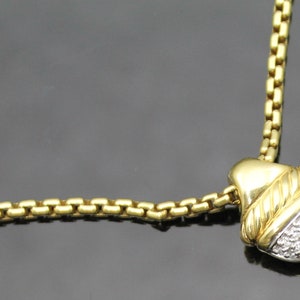 May include: A gold-toned necklace with a pendant featuring a diamond-studded, rounded bottom and a gold top. The pendant is accented with a twisted rope design. The chain is a box chain style.
