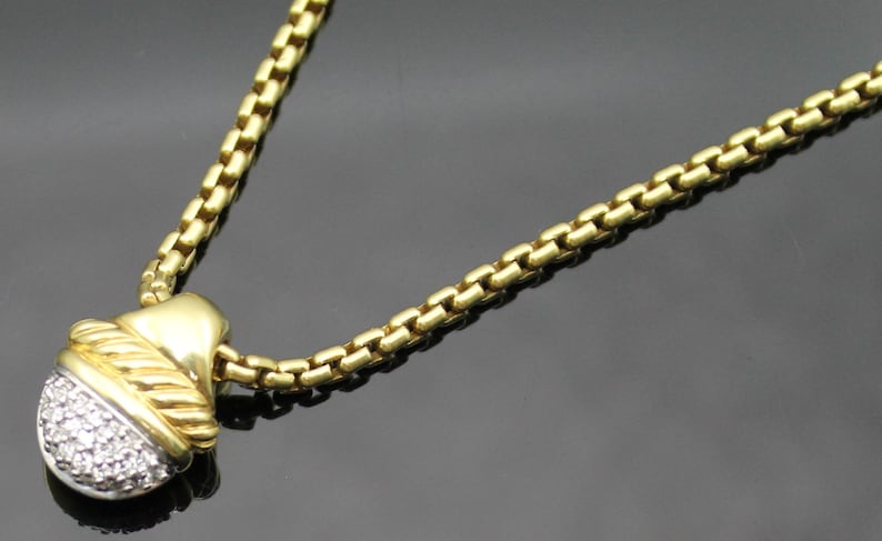 May include: Gold-toned necklace with a round pendant. The pendant features a silver-colored, gem-studded half-sphere, accented with a gold-toned twisted rope design. The chain is a gold-toned box chain.