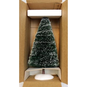May include: A small, green, conical Christmas tree with white flocking, presented in a cardboard box. The tree has a brown trunk and a white base, suggesting a miniature decorative item.