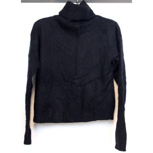 Könnte beinhalten: Ein schwarzer Rollkragenpullover mit langen Ärmeln.