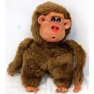 May include: A vintage plush monkey toy with a brown furry body and a tan face. The monkey has large, expressive eyes, a red nose, and open mouth. The toy is in a sitting position.