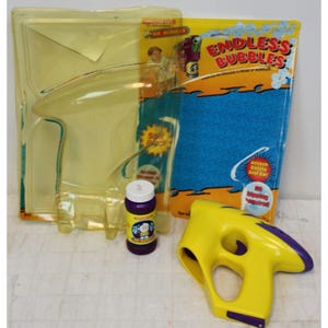 May include: A yellow and purple plastic bubble gun with a bottle of purple bubble solution. The packaging says "Endless Bubbles" and features a blue background with a cartoon character blowing bubbles.