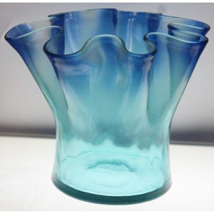 May include: A blue glass vase with a ruffled top and a gradient of color from dark blue to light blue.