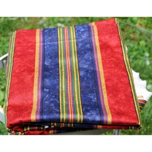May include: Folded textile with a vibrant striped pattern. The design features vertical stripes in red, blue, yellow, green, and purple. The fabric appears to be folded, showcasing the colorful design. The textile is likely a decorative item.