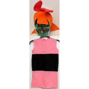 May include: A costume set featuring a bright orange hat with a red bow and a pink sleeveless dress with a black stripe across the middle. The hat has orange flaps and is designed to fit over the head.