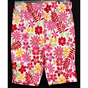 May include: White shorts with a pink, red, and yellow floral print. The flowers are large and have a tropical feel.