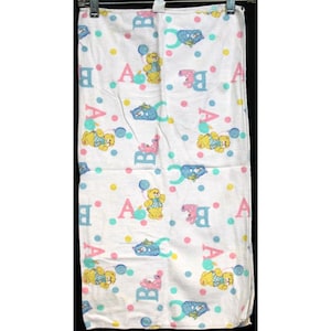 May include: White baby blanket with a repeating pattern of pink, blue, and yellow teddy bears holding balloons. The letters A, B, and C are scattered throughout the pattern.