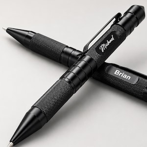 May include: Two black tactical pens with a textured knurled grip and a metal pocket clip. One pen is engraved with the name Michael in a script font, and the other pen is engraved with the name Brian in a clean, sans-serif font.