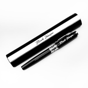 May include: A black pen and pen case set with the name "Mark Johnson" in white script. The pen has silver accents and a sleek design. The pen case is black with a white stripe.
