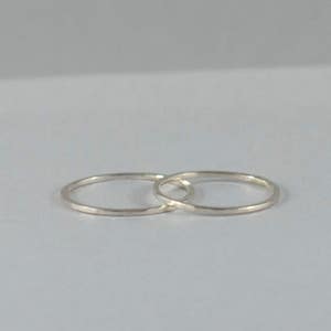 May include: Two thin silver rings, interlocked, on a white background.