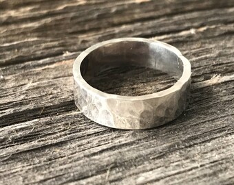 May include: A silver hammered band ring. The ring is smooth and has a textured surface.