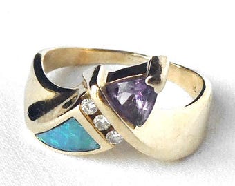 May include: Two gold rings. One ring features a triangular, purple gemstone and a gold band. The other ring has a turquoise-colored stone and three small, clear gemstones. Both rings have a polished gold finish.