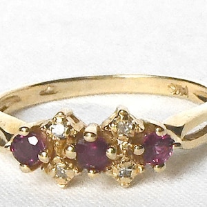 May include: A gold band ring with three ruby stones and small diamonds set in the band.