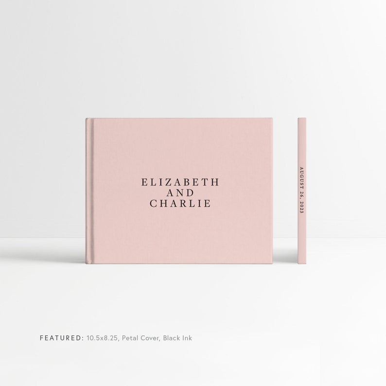 May include: A blush pink hardcover photo album with the text "ELIZABETH AND CHARLIE" and the date "AUGUST 26, 2023" printed on the spine. The album is 10.5 inches by 8.25 inches and features a petal cover with black ink.