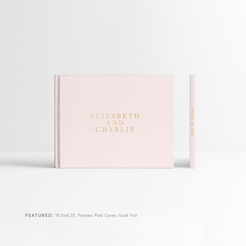May include: A blush pink hardcover photo album with gold foil lettering that reads "ELIZABETH AND CHARLIE" and "AUGUST 26, 2023". The album is 10.5 inches by 8.25 inches.