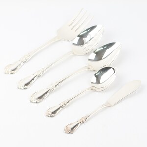 May include: A set of five silver-plated serving utensils, including a fork, a slotted spoon, two spoons, and a butter knife. The utensils have ornate handles with a floral design.