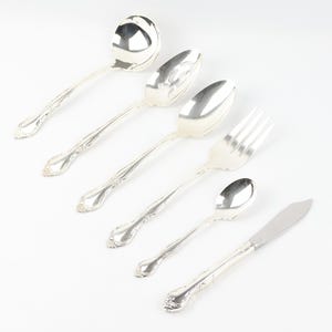 May include: A set of six silver-plated serving utensils, including a ladle, a serving spoon, a slotted spoon, a fork, a teaspoon, and a butter knife.