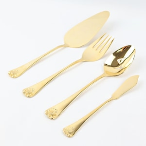 May include: A set of four gold-plated serving utensils, including a cake server, a serving fork, a slotted spoon, and a butter knife. Each utensil features an ornate, decorative design.