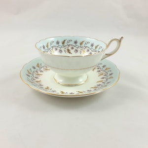 May include: A delicate teacup and saucer set with a pale blue background and a gold and purple floral design.
