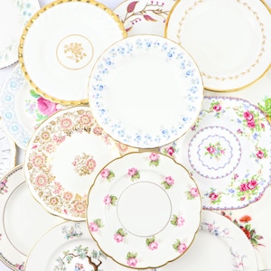 Peut inclure: Une collection de tasses à thé et de soucoupes vintage à motifs floraux avec des bordures dorées. Les assiettes sont disposées en cercle, l'assiette du centre étant la plus visible.