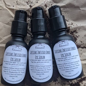 May include: Three 2 ounce bottles of caffeine infused under eye serum. The bottles are black with white labels and the text "Caffeine Infused Under Eye Serum" is printed on the front of each bottle. The ingredients are listed on the label: Caffeine Infused Avocado Oil, Almond Oil, Evening Primrose Oil, Argan Oil, Meadowfoam Oil, Vitamin E, Carrot Seed and Geranium essential Oil. The bottles are sitting on a brown surface.
