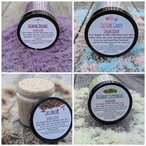 May include: Four glass jars filled with sugar scrubs. Each jar has a different color and scent: Jasmine Dreams (purple), Cotton Candy (pink and blue), Cafe Mocha (brown), and Rosemary Peppermint (green). The jars are labeled with the scent and the words "Sugar Scrub".