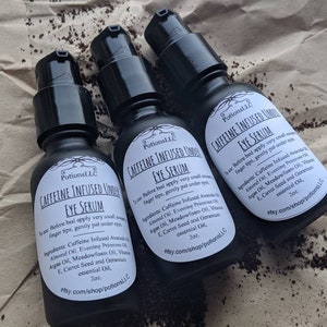 May include: Three 2 ounce bottles of Caffeine Infused Under Eye Serum. The bottles are black with white labels and the text "Caffeine Infused Under Eye Serum" is printed on the labels. The bottles are sitting on a brown paper surface.