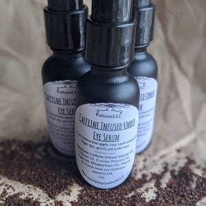May include: Three black bottles of caffeine infused under eye serum with a black pump top. The bottles are labeled "Potions LLC Caffeine Infused Under Eye Serum 2oz. etsy.com/shop/potionsLLC"