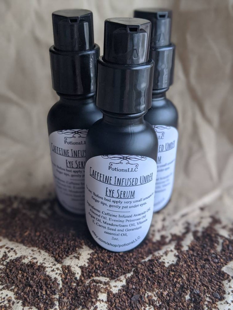 May include: Three black bottles of caffeine infused under eye serum with a black pump top. The bottles are labeled "Potions LLC Caffeine Infused Under Eye Serum 2oz. etsy.com/shop/potionsLLC"