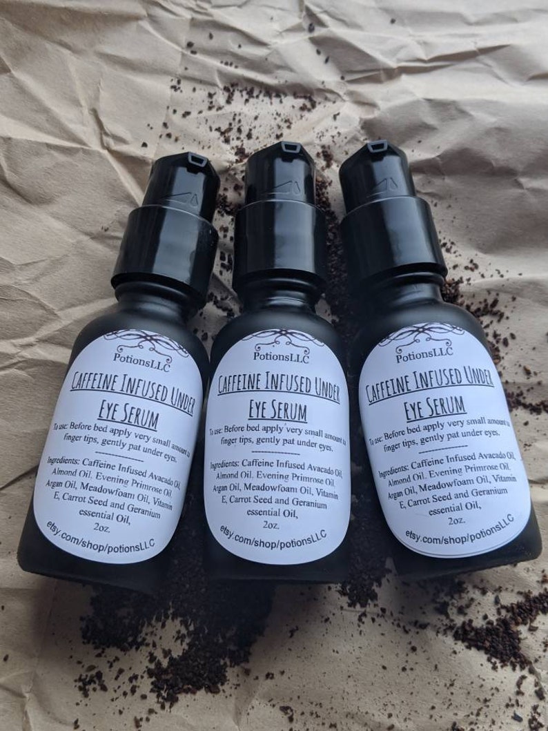 May include: Three 2-ounce bottles of caffeine infused under eye serum. The bottles are labeled with the text "Caffeine Infused Under Eye Serum" and "PotionsLLC". The bottles are on a brown paper background.