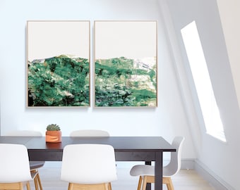 Puede incluir: Dos pinturas abstractas de paisajes en tonos verdes y blancos, enmarcadas en madera natural, colgadas en una pared blanca sobre una mesa de comedor de madera oscura con cuatro sillas blancas.