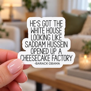 Op de afbeelding: Een witte, uitgesneden sticker met zwarte tekst: HE'S GOT THE WHITE HOUSE LOOKING LIKE SADDAM HUSSEIN OPENED UP A CHEESECAKE FACTORY -BARACK OBAMA. De sticker heeft een gladde, matte afwerking en een strak, afgerond ontwerp.