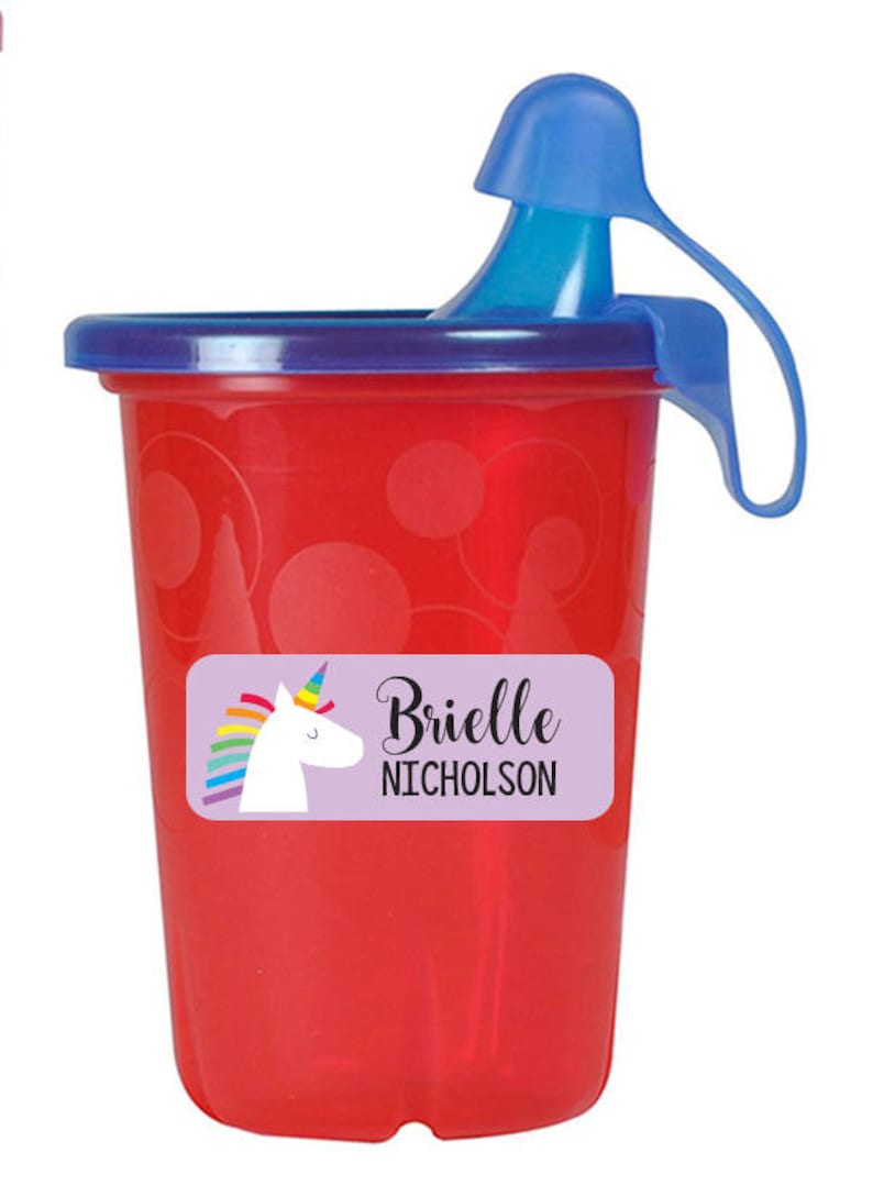 May include: Red plastic cup with a blue lid and handle. The cup has a purple label with a unicorn and rainbow design. The label says "Brielle Nicholson".
