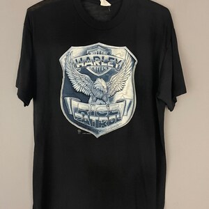 May include: Black t-shirt with a white graphic of an eagle holding a Harley Davidson logo with the text "Ride Patrol" and "Rolling America's Highways".