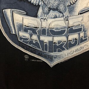May include: Black t-shirt with a graphic of an eagle holding a banner that reads "Ride Patrol America's Highways". The banner is blue and white with a Harley Davidson logo.