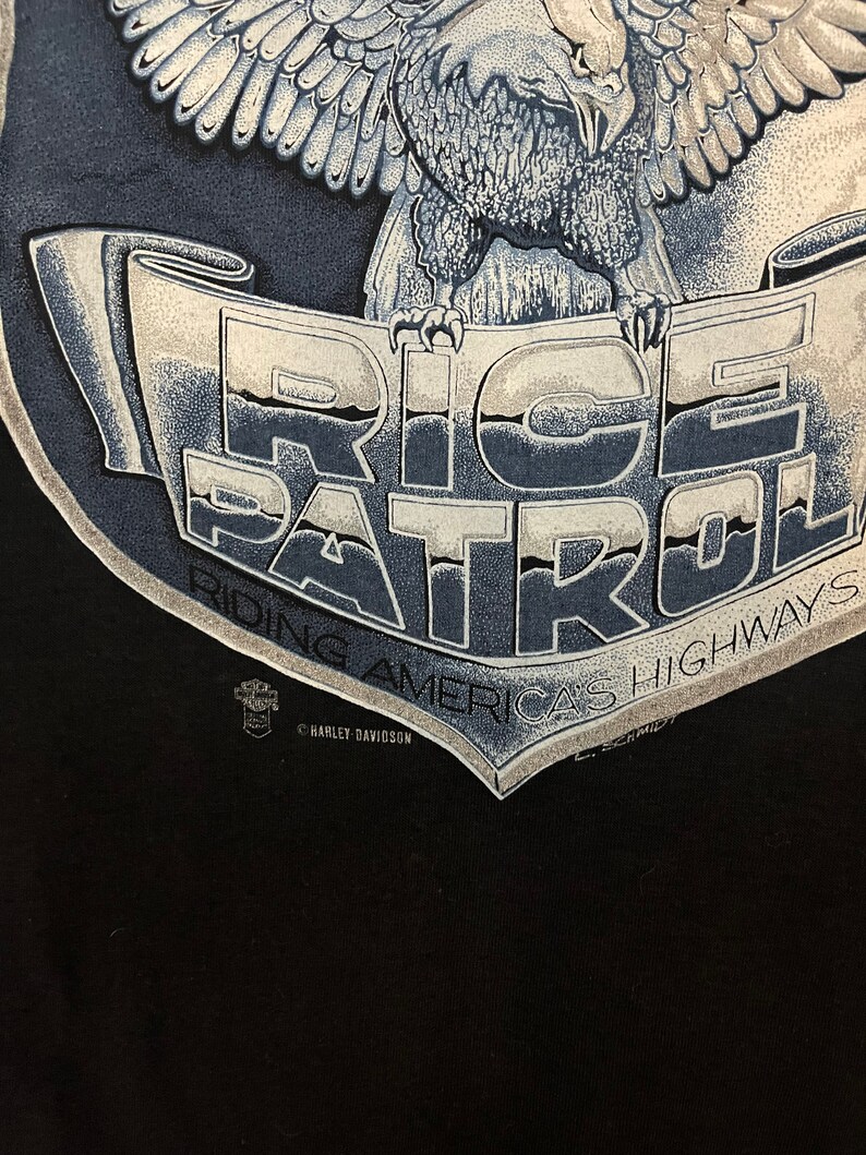 May include: Black t-shirt with a graphic of an eagle holding a banner that reads "Ride Patrol America's Highways". The banner is blue and white with a Harley Davidson logo.