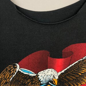 May include: Black t-shirt with a red, white, and blue American flag design featuring a bald eagle with outstretched wings and the words "MOTOR HARLEY DAVIDSON".